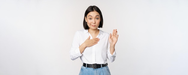 Imagen de una linda joven oficinista asiática estudiante levantando la mano y poniendo la palma en el pecho na