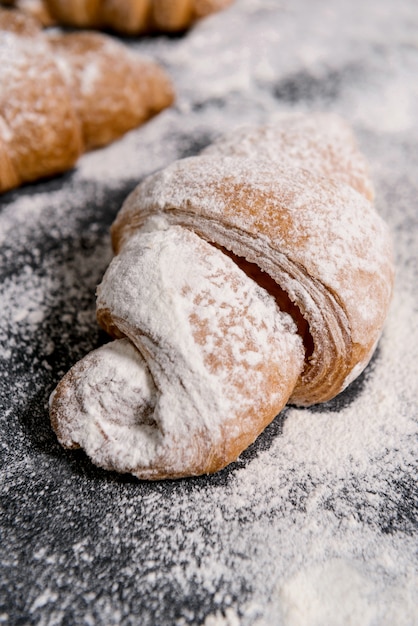 Imagen macra de cruasanes con el azúcar en polvo en la tabla gris.