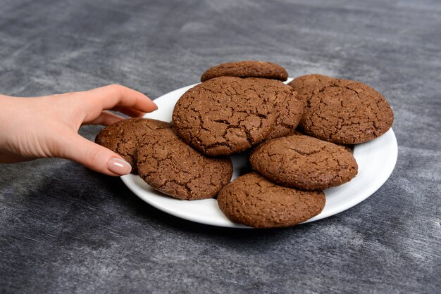 Imagen de manos sosteniendo galletas de chocolate sobre superficie de madera