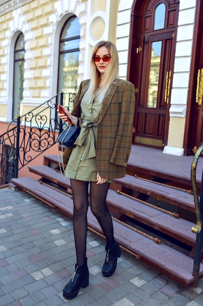 Imagen de moda al aire libre de mujer modelo rubia impresionante posando en la calle de París, traje de moda con chaqueta moderna de gran tamaño, otoño primavera a mitad de temporada, colores cálidos.