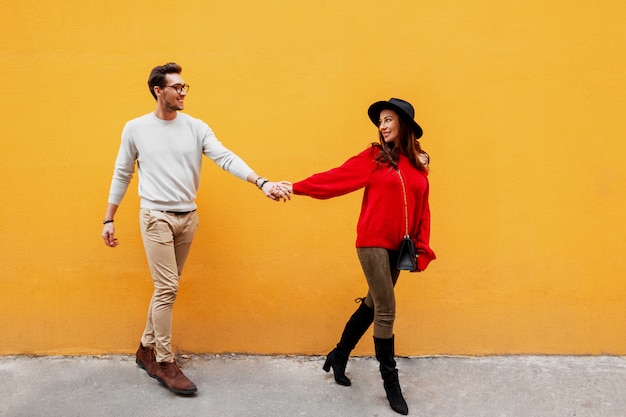 Imagen de moda otoño de elegante elegante pareja de enamorados cogidos de la mano y mirando el uno al otro con placer.