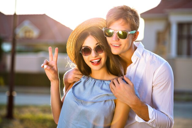 Imagen de moda de verano de una elegante pareja de estilo vintage en el romántico día de San Valentín, pasando un buen rato juntos, abrazos y besos, hipsters, ropa elegante y gafas de sol, hermosos amantes, familia al aire libre