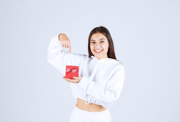 Imagen de una modelo bastante joven apuntando a una caja de regalo.