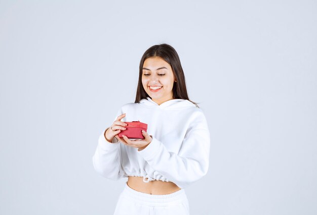 Imagen de una modelo bastante joven sosteniendo una caja de regalo.