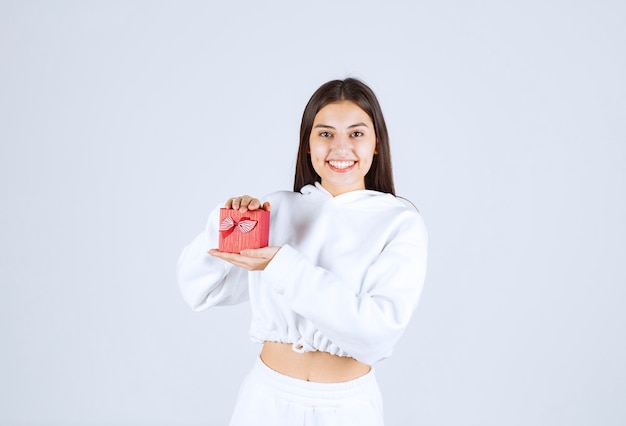 Imagen de una modelo bastante joven sosteniendo una caja de regalo.