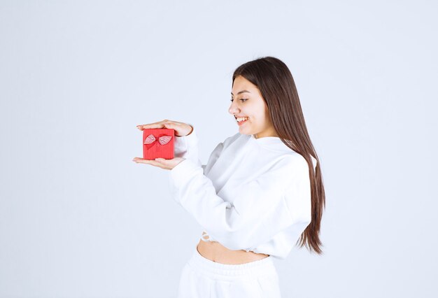 Imagen de una modelo bastante joven sosteniendo una caja de regalo.