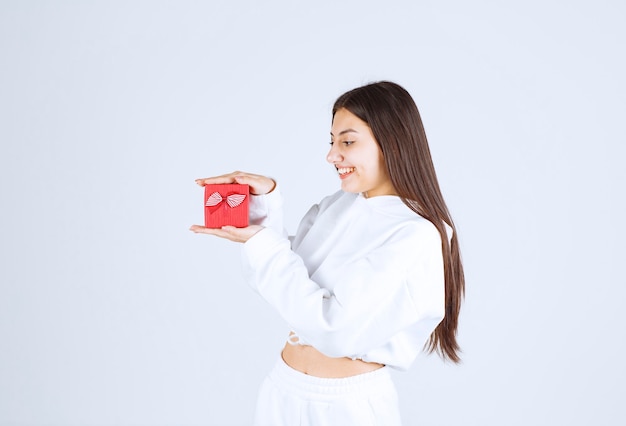 Imagen de una modelo bastante joven sosteniendo una caja de regalo.