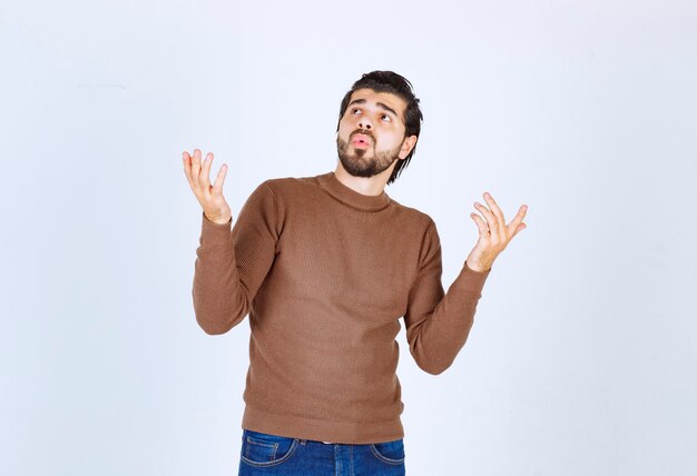 Imagen de un modelo de hombre guapo joven de pie y mirando hacia arriba sorprendentemente. Foto de alta calidad