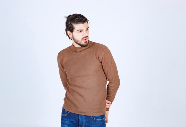 Imagen de un modelo de hombre guapo joven de pie y posando sobre una pared blanca. Foto de alta calidad