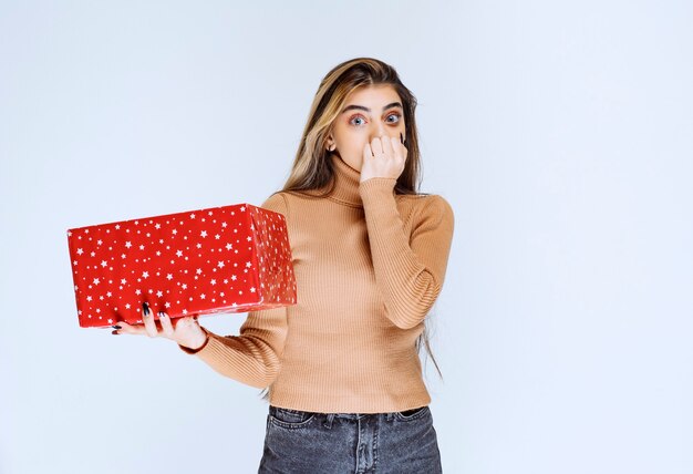 Imagen de un modelo de mujer atractiva sosteniendo un regalo rojo.