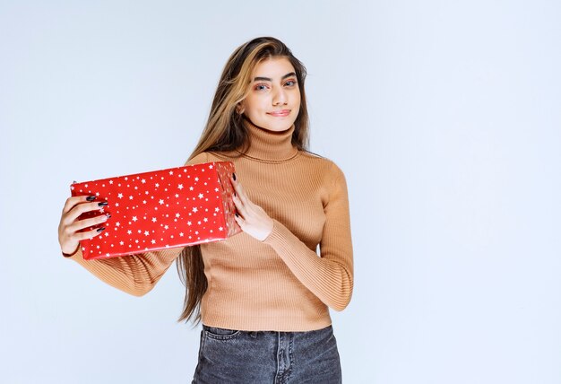 Imagen de un modelo de mujer atractiva sosteniendo un regalo rojo.