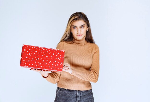 Imagen de un modelo de mujer atractiva sosteniendo un regalo rojo.