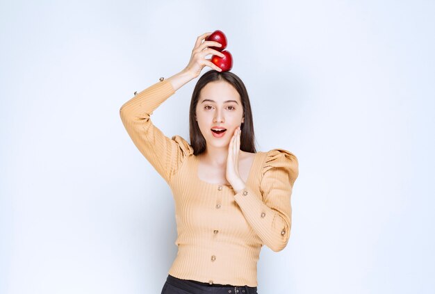 Imagen de un modelo de mujer bonita de pie y sosteniendo manzanas rojas frescas.