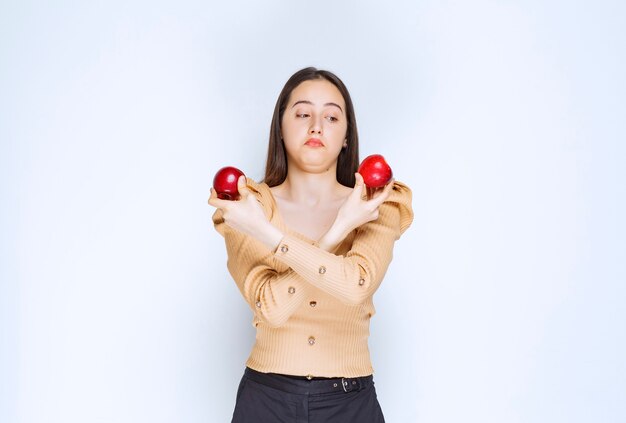 Imagen de un modelo de mujer bonita de pie y sosteniendo manzanas rojas frescas.