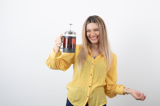 Imagen de un modelo de mujer bonita sonriente sosteniendo una tetera.