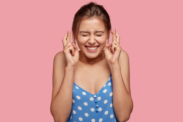 Imagen de mujer alegre complacida cruza los dedos