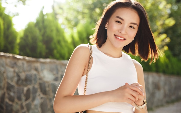 Imagen de la mujer asiática moderna de pie en el parque y sonriendo