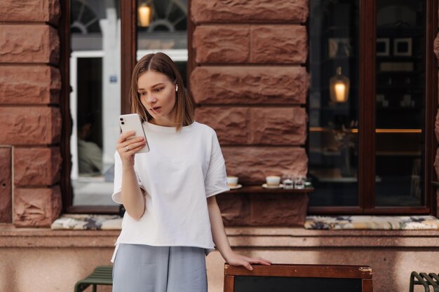 Imagen de una mujer atractiva sosteniendo un teléfono con una camiseta blanca