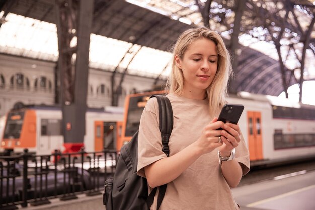 Imagen de una mujer atractiva sosteniendo un teléfono en la estación de tren