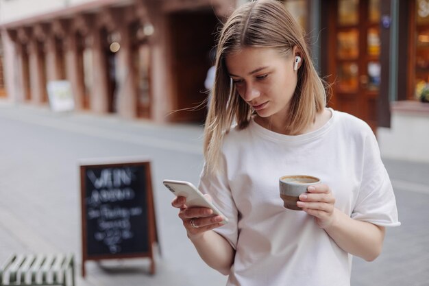 Imagen de mujer de cabello rubio mira el teléfono con café