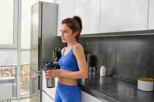 Foto gratuita imagen de una mujer en forma y saludable en ropa deportiva bebiendo agua sosteniendo una botella y agitando