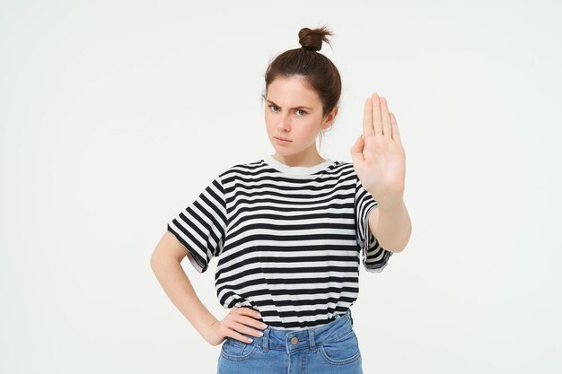 Foto gratuita imagen de una mujer hermosa con cara seria que muestra una señal de parada extiende una palma y frunjea el ceño