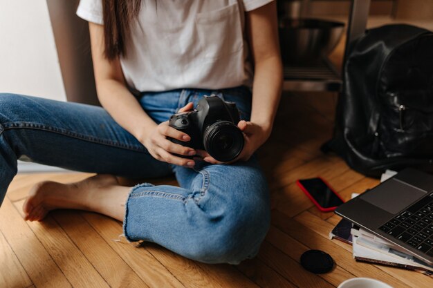 Imagen de mujer en jeans sentada en el piso con frente, laptop y teléfono