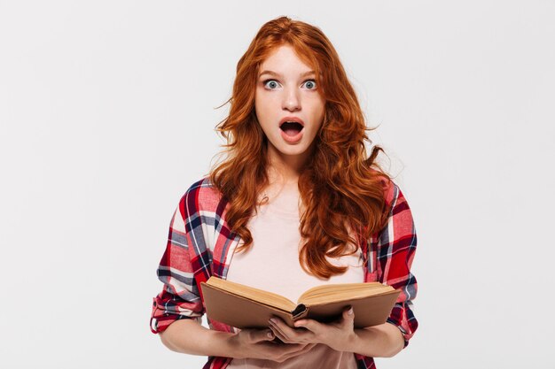 Imagen de mujer de jengibre sorprendida en camisa con libro