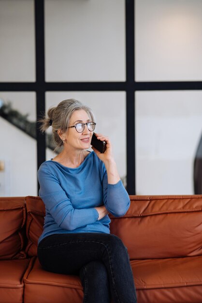 Imagen de mujer mayor hablando por teléfono inteligente en casa