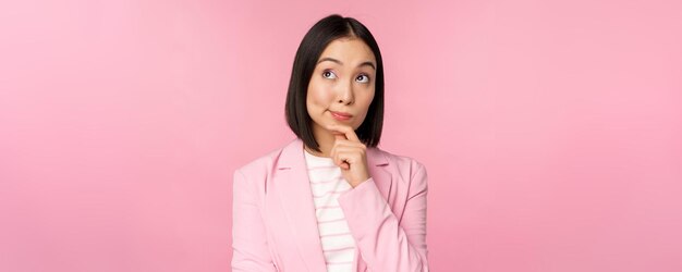 Imagen de una mujer de negocios asiática parada en una pose de pensamiento usando un traje de vendedora coreana e