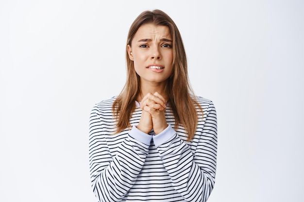 Imagen de mujer nerviosa y miserable pidiendo ayuda, suplicándole, diciendo por favor con rostro desesperado y necesitado, de pie en blanco