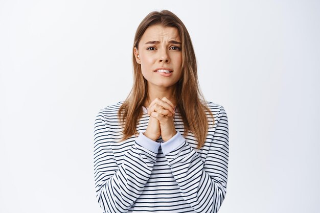 Imagen de mujer nerviosa y miserable pidiendo ayuda, suplicándole, diciendo por favor con rostro desesperado y necesitado, de pie en blanco