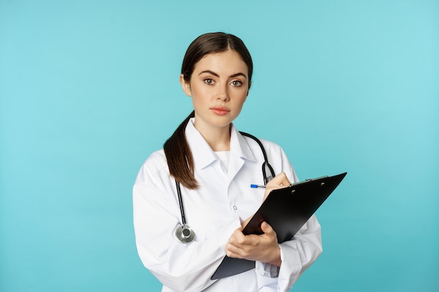 Imagen de mujer profesional médico médico con portapapeles escribiendo escuchando paciente en cl...