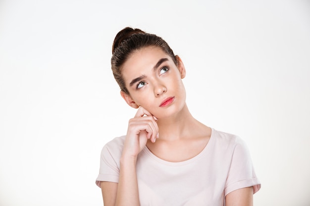 Imagen de mujer seria con cabello castaño en moño con cara hacia arriba pensando o soñando posando