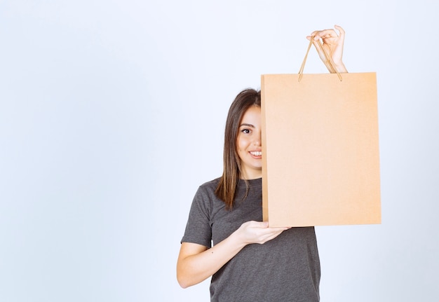 Imagen de mujer sonriente sosteniendo una bolsa de papel y posando.