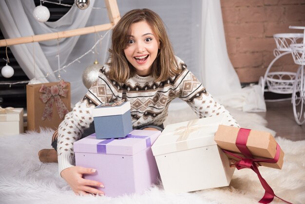 Imagen de una mujer sonriente sosteniendo un regalo de Navidad en la sala de estar.