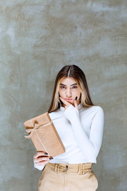 Imagen de una niña modelo sosteniendo un papel presente sobre piedra