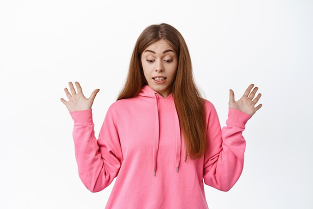 La imagen de una niña se ve sorprendida hacia abajo con las manos extendidas hacia los lados y deja caer algo mirando hacia abajo de pie sobre un fondo blanco