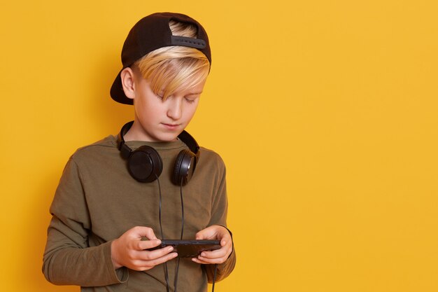 Imagen de un niño con auriculares alrededor de su cuello, un chico con camisa verde enebro y visera negra