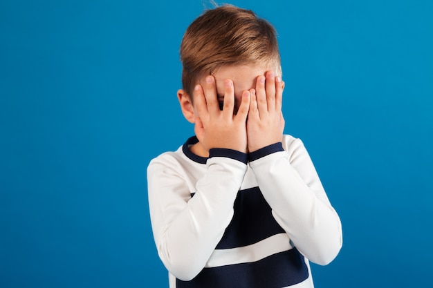 Imagen de un niño en suéter cubriéndose la cara