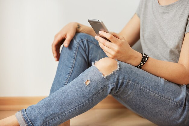 La imagen del primer de un adolescente está buscando información en la red en el teléfono móvil