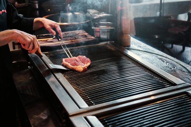 Imagen de primer plano de un delicioso filete de carne cocinado a la parrilla en la cocina de un restaurante.