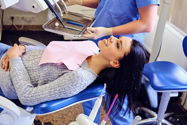 Imagen de primer plano de un dentista que examina los dientes de una mujer en odontología.