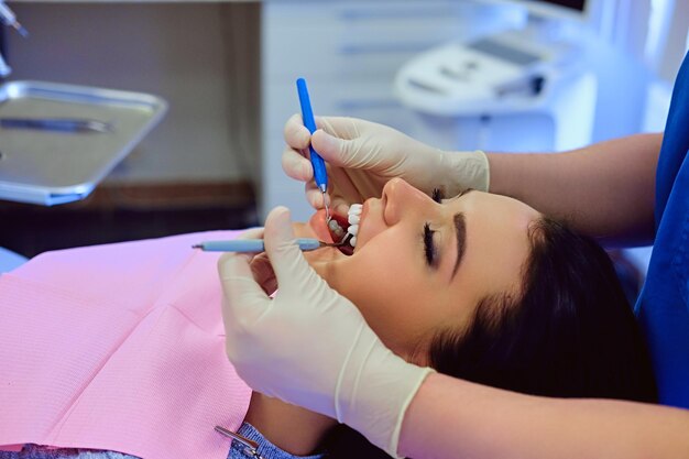 Imagen de primer plano de un dentista que examina los dientes de una mujer en odontología.