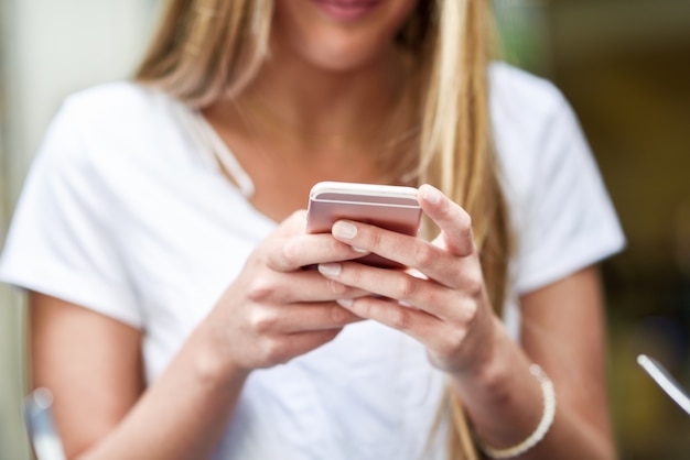 Imagen de primer plano de joven rubia chica mensajes de texto con smartphone