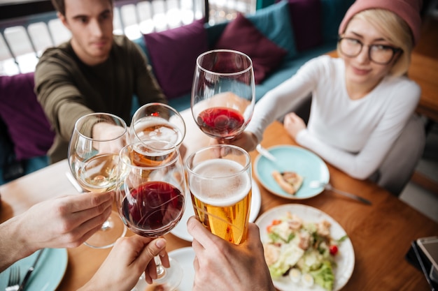 Imagen recortada de amigos sentados en la cafetería bebiendo alcohol.