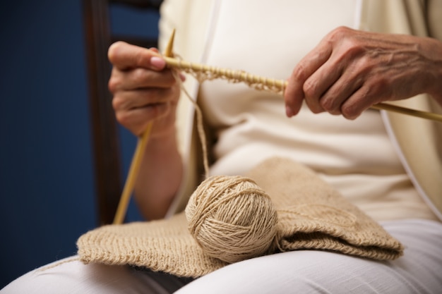 Imagen recortada de anciana tejiendo.