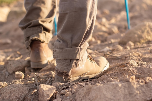 Imagen recortada de botas de montaña. Persona con pantalones rotos con palos especiales subiendo. Hobby, naturaleza, concepto de actividad al aire libre.