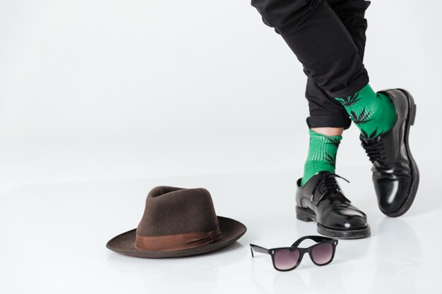 Imagen recortada hombre parado en el piso cerca del sombrero y gafas de sol