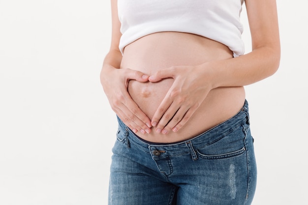 Foto gratuita imagen recortada de mujer embarazada sosteniendo sus manos sobre la barriga